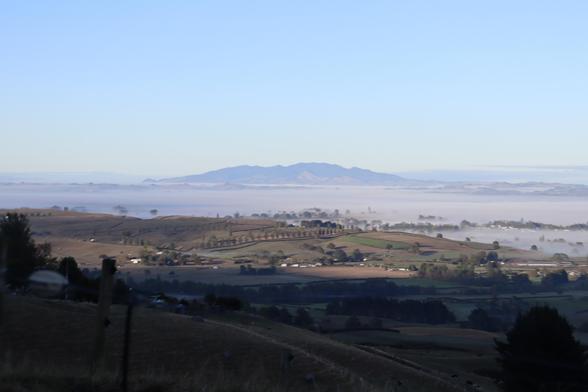 Out of a sea of fog rises a dark forested mountain some 30 or so kilometres away. A brilliant blue early morning sky is overhead