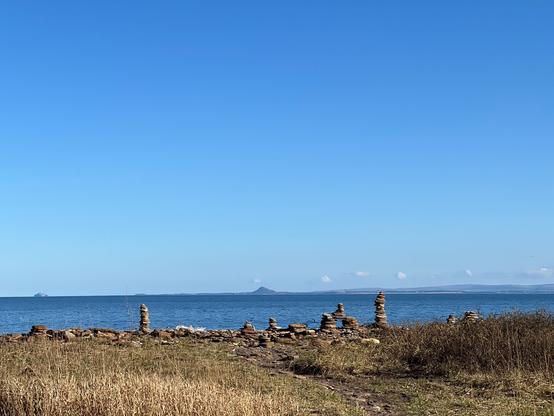 View from the coast onto the sea with a couple of stone men in the front.