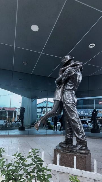 Bronze sculpture of a man and a woman hugging. Reflective walls on the background.
