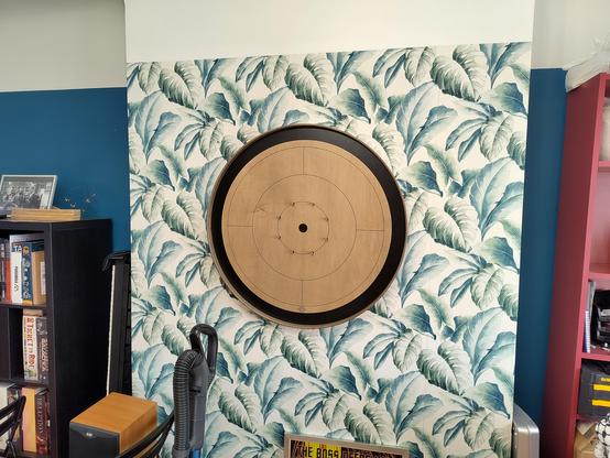A crokinole board (traditional wooden Canadian disk flicking game) hangs in the middle of a wall in a home.
