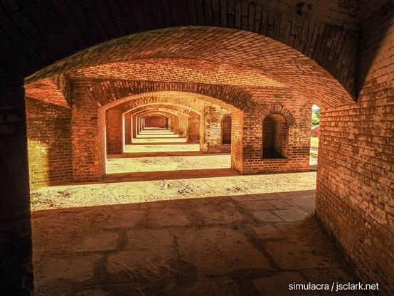 Gallery of brick arches inside a fort, lit by late sun.