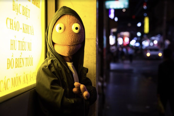 image from eutoday.net

Randy Feltface wearing a windbreaker with the hood up and arms folded facing the camera while leaning against a brightly lit store window. The right side of the background is a blurry photo of street at night. there are blue and yellow building signs at different heights and a cars headlights in the distance.