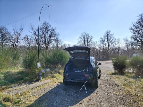 Kleinwagen mit geöffneter Heckklappe auf dem Hügel. Links daneben steht der Antennenmast.