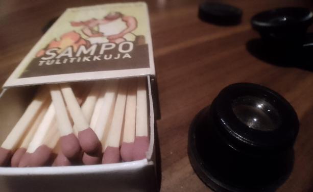 A matchbox and some smartphone camera accessory lenses on a table.

A macro shot.