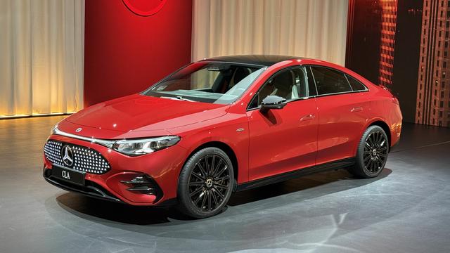 Photo of a red Mercedes-Benz CLA in 3/4 driver's side view on a gray floor with a red and off-white background