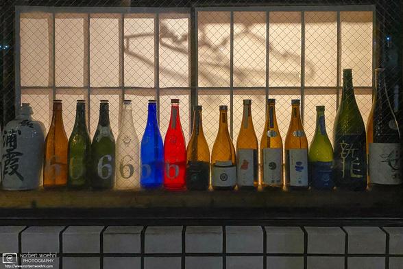 In a window of a restaurant in the Shimura area of Itabashi Ward in Tokyo, Japan, colorful bottles are lined up in front of an illuminated interior.