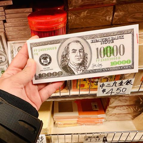 A photo of a fake currency note. It says 10000 and looks like a US dollar note but has a fake president and says Heaven’s Bank