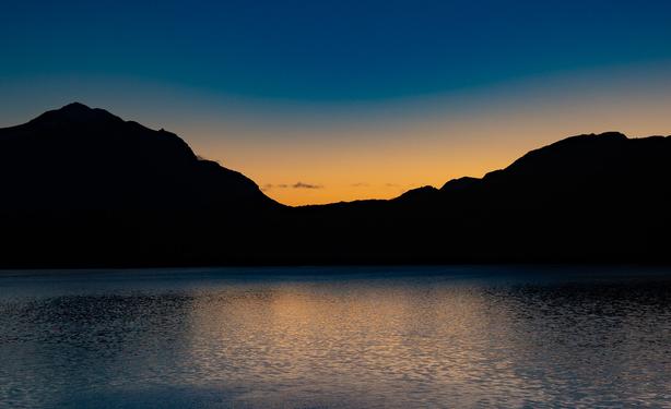 Pre sunrise blue and golden sky with dark hills.