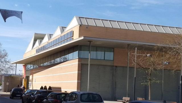 Vista des del carrer d'un poliesportiu. A la façana on pega el Sol, a la part més alta hi ha dues fileres de plaques solars.