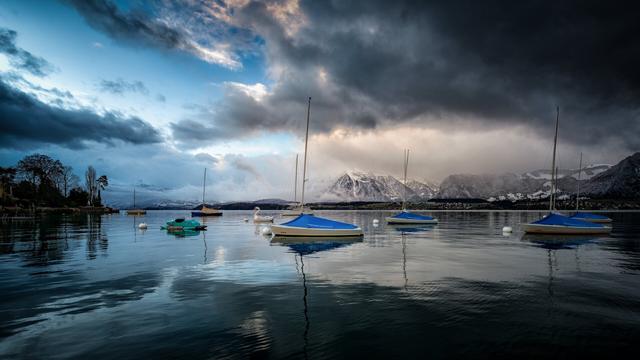 Dramatisches Wetter am Thunersee mit Segelbooten an Bojen und einem Schwanen-Pedalo