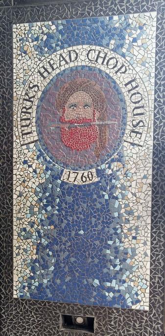 Mosaïque représentant une tête d'homme barbu roux avec une dague entre les dents. Encadré par la mention Turk's Head Chop House