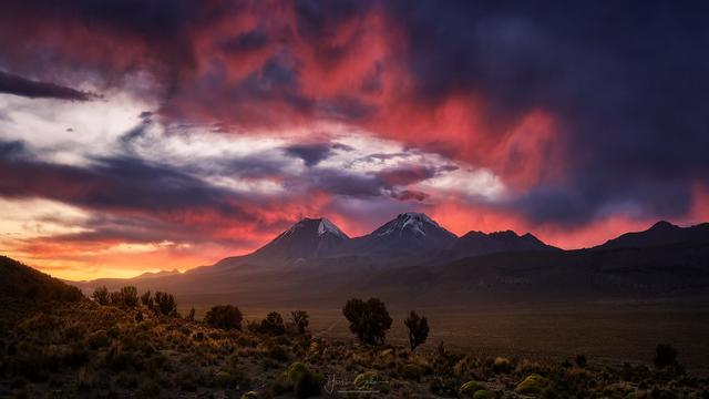 El atardecer sobre los nevados Parinacota y Pomerape, dos volcanes gemelos en la frontera entre Chile y Bolivia, es un espectáculo único. Mientras el sol se oculta, las cumbres nevadas de estos colosos, de más de 6,000 metros de altura, se tiñen de colores, creando una vista impresionante que refleja la majestuosidad y el misterio de los Andes.