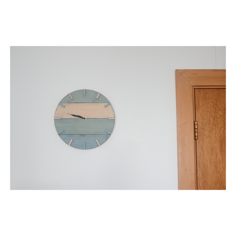 a clock with no numbers on a white wall with a wooden door frame beside it