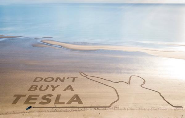 Ein Strand aus der Luft: jemand hat in den Sand riesig geschrieben „Don‘t buy a Tesla“