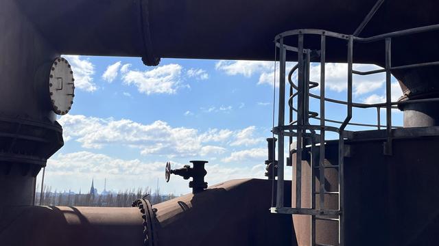 Dicke Rohre aus Metall lassen einen Blick auf Himmel und Stadt frei. Fotografiert vom Hochofen aus.

Thick metal tubes leave a view of the sky and the city free. Photographed from the blast furnace.