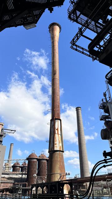 Hoch in den strahlenden Himmel ragen die Schlote des ehemaligen Hüttenwerks zur Roheisen-Produktion

High in the bright sky rise the moats of the former metallurgical plant for the production of pig iron