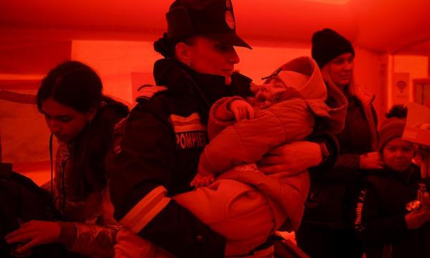 Una bombera atiende a un niño refugiado tras cruzar el paso Isaccea-Orlivka entre Ucrania y Rumanía, el 25 de marzo d de 2022. (LAPRESSE)