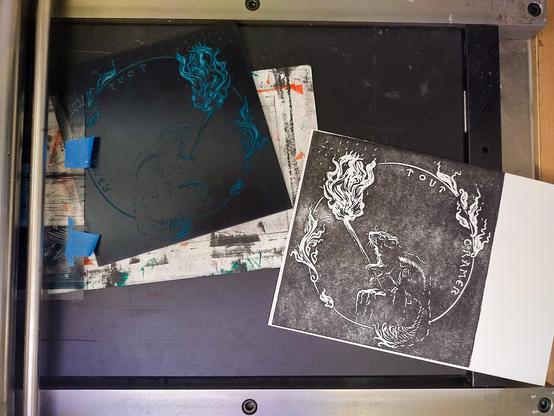 A flatbed letterpress with a linocut and its print featuring a squirrel with a torch. A text reads "Tout cramer" (Burn down everything)
