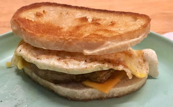 Photo of my breakfast sandwich from this morning. Homemade sourdough bread, sliced thin, buttered on one side and pan fried (on the buttered side) to toast golden brown and crispy.

American Cheese slice, ripped in half so neither over-ran the edge of the bread.

A Beyond Meat Spicy Breakfast Sausage was fried in a separate pan, then cut into quarters to place evenly on the somewhat semi-circular bread. Then a fried egg added, before setting the other slice of toasted, cheesed bread on top.