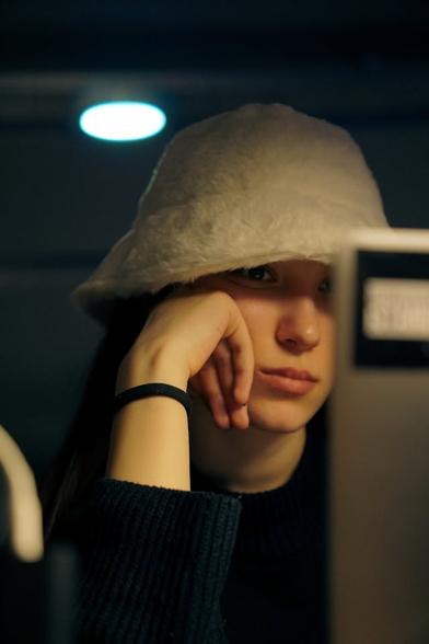 A woman, perhaps looking at No Fap for women, with a hat on, leaning on her hand staring at a laptop screen.