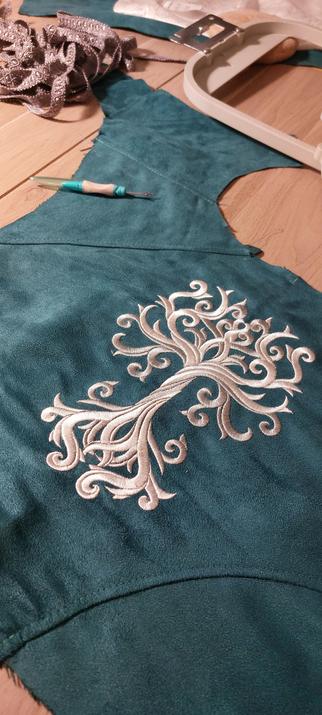 Broderie blanche et grise représentant un arbre de vie elfique sur un tissu en suédine vert pétrole