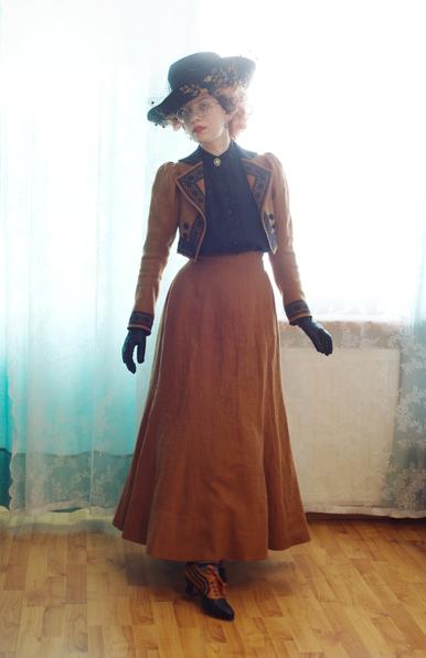 A dashing little full body portrait of Sini taking a step forward in the ensemble described in the first post of the thread. The geometric lines of the jacket, with two little buttons captured by the lace edging, are a nice contrast to the smooth softness of the line of the skirt. She's gazing at the camera and thus the viewer, in a light filled living room, backlit against some sheer curtains. The little dots in the veiling seem to float in mid air on the dainty veil of the hat.