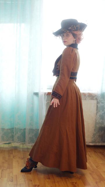 Side view, with another jaunty step and extension of ankle. She is looking back at the viewer again, looking rather cute in her enormous hat and round glasses. The sleeve here falls nicely, the full volume of the back of skirt is seen, and there's even a peek of sock... Which is a gray stripe and the wrong colour for the ensemble!