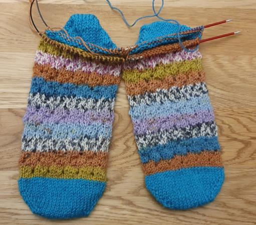 2 socks being knitted two at a time in circular needles, from the toe up, in self striping yarn, where I just turned the heels in a matching solid color
2 chaussettes en cours de tricot depuis la pointe, sur des aiguilles circulaires, en laine auto rayante, juste après avoir tourné les talons dans une couleur unie assortie