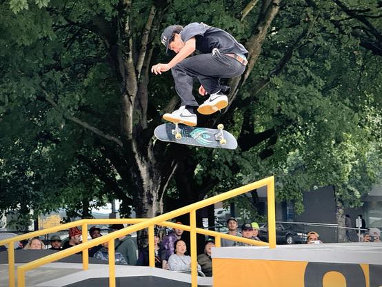John Bradford performs a 360 flip over a rail on a mostly cloudy day.