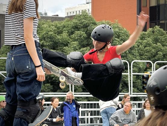 A female skateboarder performs a frontside stalefish grab in the bowl on a mostly cloudy day.