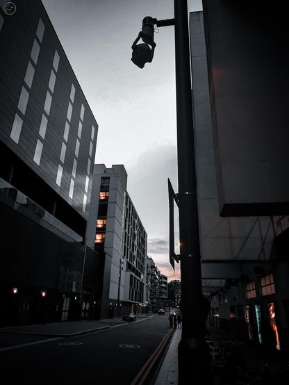 Evening shot on London street with towering buildings either side and the glow from window lights and vending machines