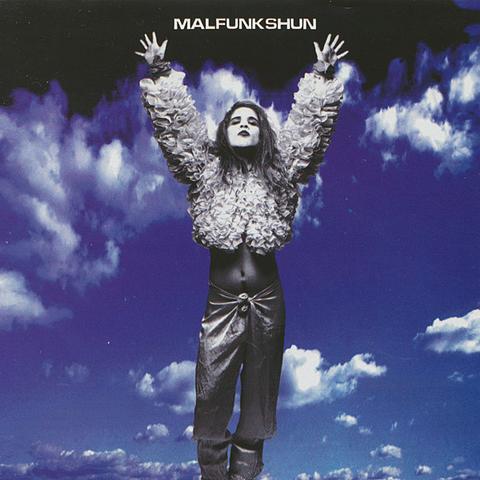 The cover art is a black and white photo of Andrew Wood, against a background of a blue sky with white clouds. Andrew is wearing a cropped sweater with a ton of ruffles on it and low-slung pants that are tied in a knot in the front. He has long hair, eye/lip makeup on as well as white face paint, and has both hands raised, midriff exposed, looking at the camera. The band name is in white font at the top center.