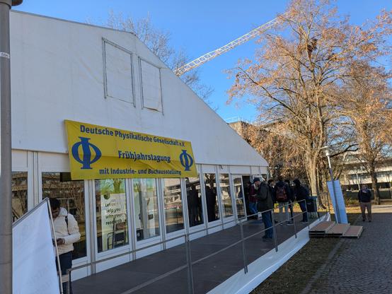 Blick auf das weiße Ausstellungszelt (Festzelt) der DPG-Frühjahrstagung mit blau-gelben Infobanner