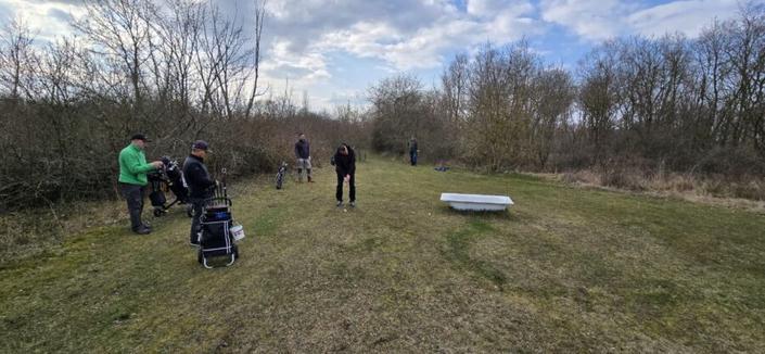 Ein Crossgolf Spieler versucht seinen Golfball in eine auf einer Wiese stehende Badewanne zu spielen