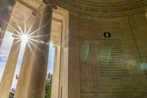 Sunlight peeks through the columns of the Jefferson Memorial, illuminating the historic text within, in Washington, D.C.