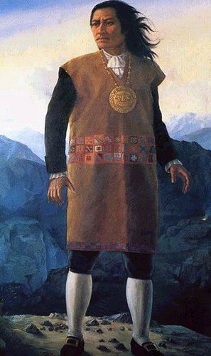Painting of Tupac Amaru II, standing in front of mountains, wearing a brown tunic, with a medallion around his neck. By Unknown author – http://peru.feeder.ww7.pe/index.php?cal_date=2009-07-29, Public Domain, https://commons.wikimedia.org/w/index.php?curid=9105047