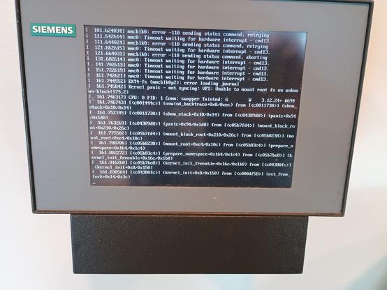 Ein Mini-Wand-Bildschirm mit Siemens-Logo zeigt Zeilen einer "Kernel Panic"