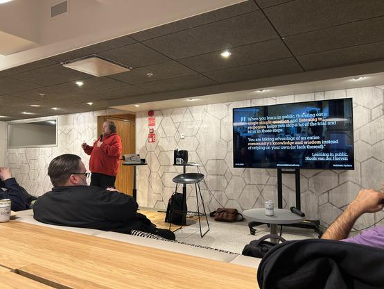 Juhis on stage with a slide encouraging learning in public.