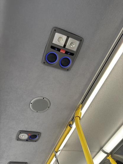 A small module with reading lights and a speaker are seen embedded in the ceiling. There is a yellow safety bar attached nearby.