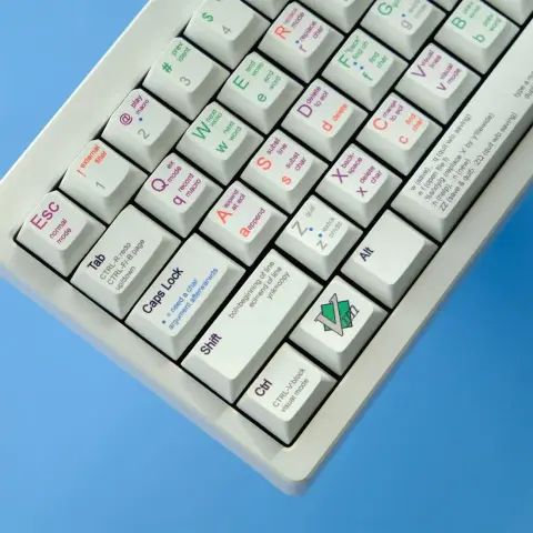 A photo of a mechanical keyboard with custom keycaps, each showing Vim notes for the corresponding key.