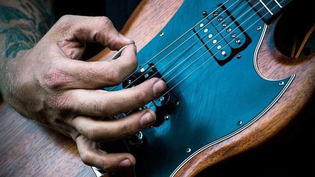 Close-up photo of a guitarist playing an SG style Guitar