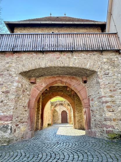 Das Bild zeigt eine steinerne Tor-Durchfahrt durch eine meterdicke Stein-Wand oder Wall-Anlage und gibt den Blick frei auf weitere Torbögen und Tore.
