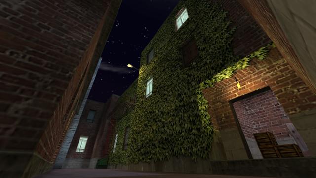 In this picture you can see the alley when you come out of the hallway from the previous picture. You can also look into the hallway again. Because here, too, the entrance, where a yellow-lit lamp hangs from the ceiling, is open. In the hallway there are three wooden boxes, two of which are stacked on top of each other. The entrance is free of ivy, but not the rest of the brick building, which is mainly wrapped in ivy. You can see a total of eight windows on the building. Of these, light burns in four rooms. Two windows have metal grilles and one is provided with a wooden board. A yellow illuminated lamp is attached to one corner of the brick building. There is also a red ladder on the building that leads to a platform on the first floor of the building. Next to the ladder is a dumpster. This is on the map cs_backalley in the game Counter-Strike 1.6.