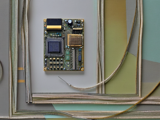 An electronic board with intricate components and circuits, mounted on a grey section of wall painted with modern teal, green, and gold elements, and surrounded by shielded wires covered in a faraday mesh. One wire below the board has an exposed connection.