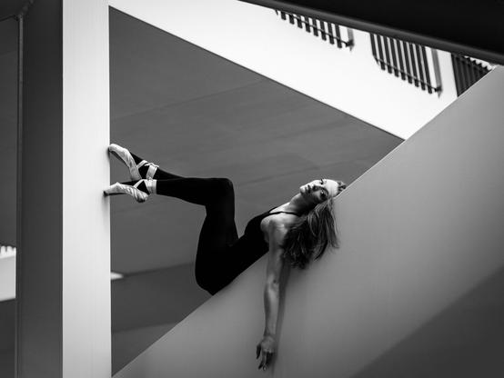 Ballerina, die auf dem Geländer einer Außentreppe liegt