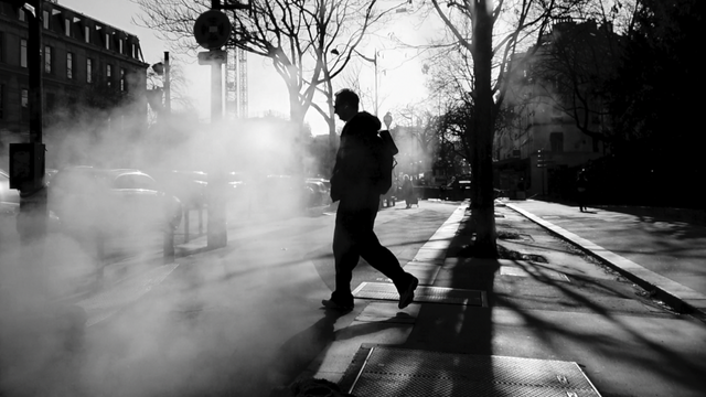 Images de l'instant présent : Image en noir et balnc d'un homme dans la rue à Paris qui traverse un épais nuage de fumée blanche