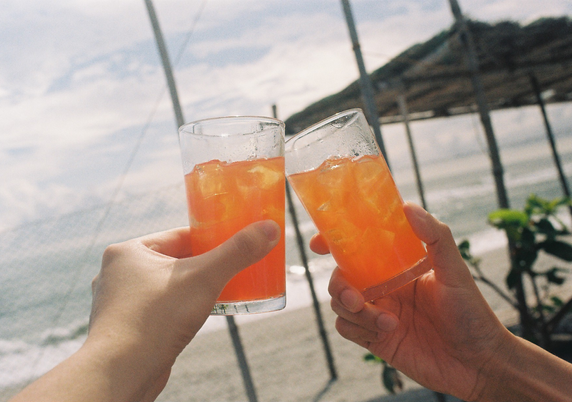 Clinking two drinks at the beach.