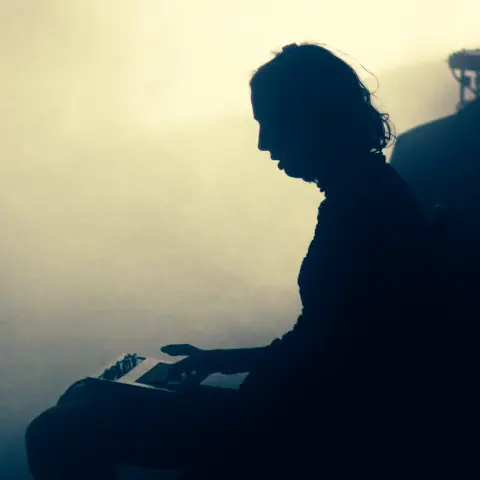 Photo de la chanteuse du groupe UTO en contre jour, en train de jouer du clavier sur ses genoux