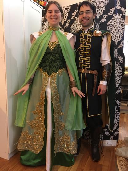 See description from previous photo of woman and man. The additional draped silk piece worn by the woman attaches at the neck on a green satin band that has gold beaded lace flowers hiding the hook and eye clasp. The veil drapes open in the front to knee length and wraps around the back loosely draping.