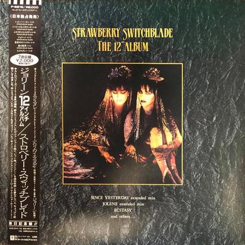 The sleeve of the Japanese release The 12 Inch Album. It has an atmospheric photo of Strawberry Switchblade lit by candlelight, placed in the centre of a slate textured background.